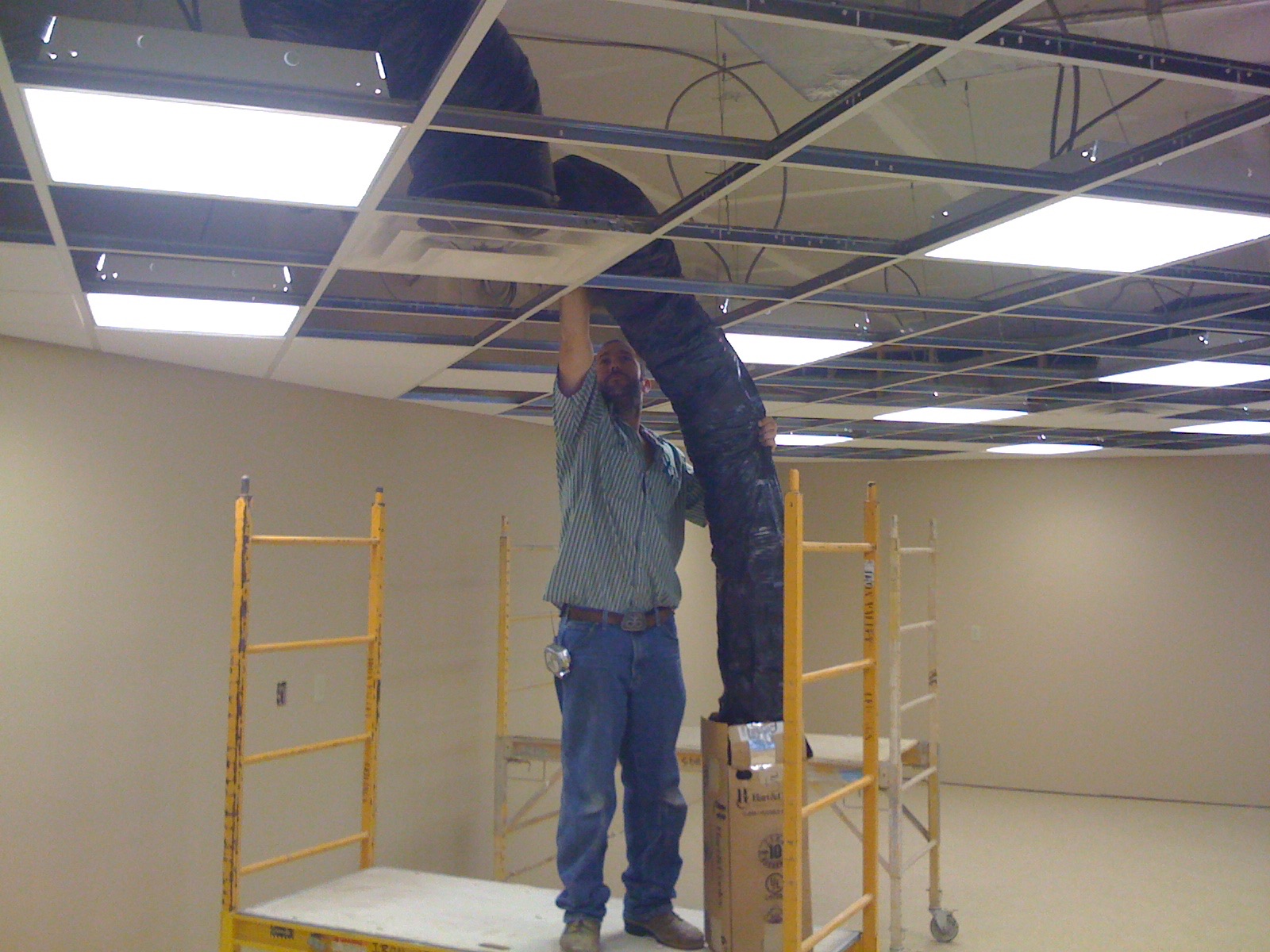Worker installing overhead mechanical lines in an interior space